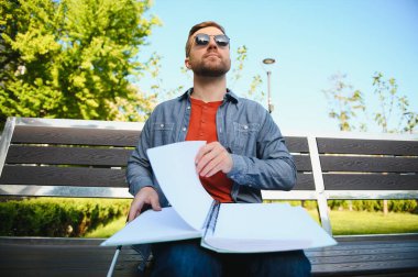 Kör adam parkta bankta kitap okuyor..