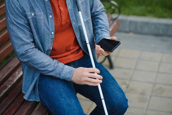 Young blinded man using phone and sending voice message.