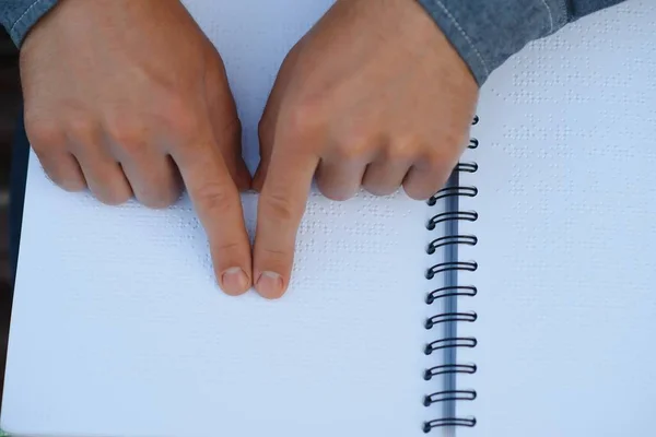 Blinded man reading by touching braille book.