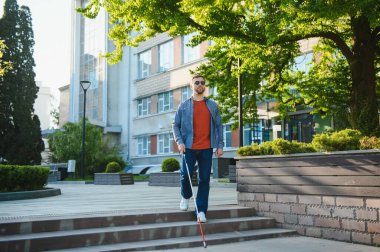 sopa tutan kaldırımda yürüyen kör adam.