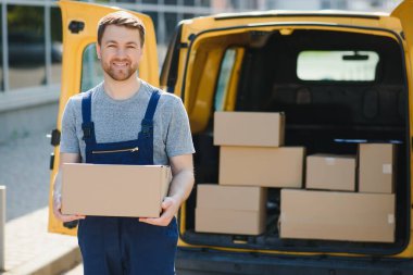 Teslimat servisi çalışanı. Teslimat servisinde çalışan bir adamın portresi. Kutulu kurye portresi. Minibüsün yanındaki kurye. Teslimat servis kariyeri