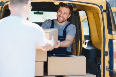 Malların teslimatı için kurye servisi. Ekspres servis üniformalı bir adam kutuları teslim eder. Çalışan siparişi müşteriye götürür.