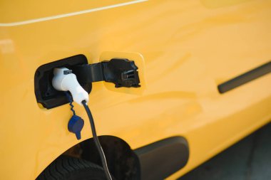 Yakışıklı sakallı adam şarj istasyonundaki yeni modern elektrikli arabasının yanında..