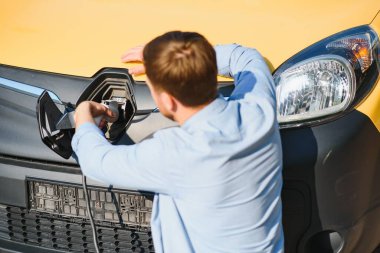 Gülümseyen adam araba şarj cihazını prizden.