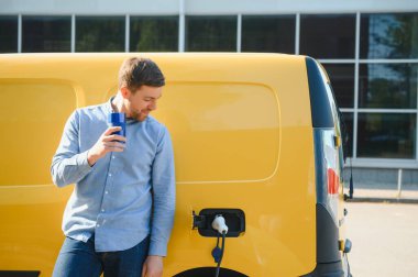 Evin yanında elektrikli araba şarj eden bir adam var..