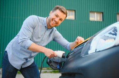 Gülümseyen adam araba şarj cihazını prizden.