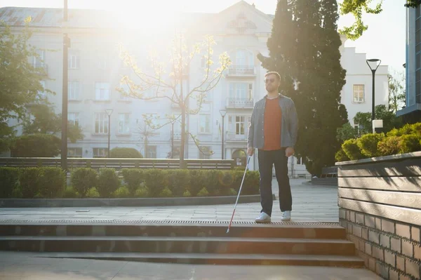 Blind Man Walking On Sidewalk Holding Stick.