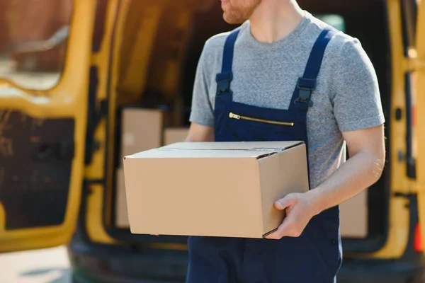 delivery service employee. Portrait of man working in delivery service. Portrait of courier with box. Courier next to minivan. Delivery service career