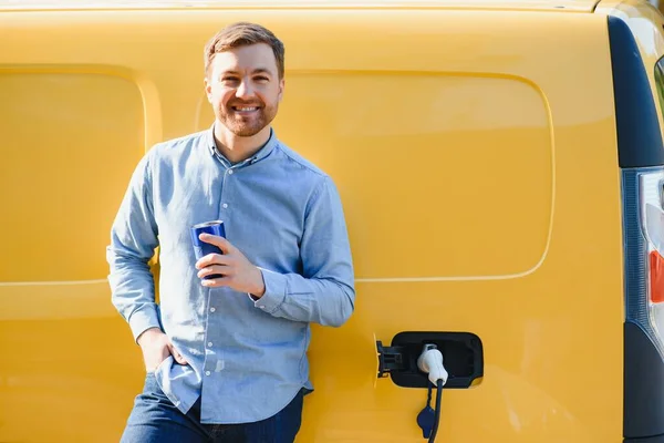 Schöner Mann Trinkt Kaffee Beim Laden Von Elektroautos — Stockfoto