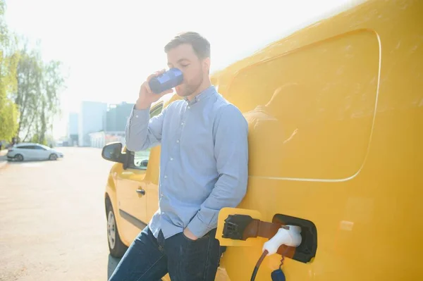 Yakışıklı Adam Elektrikli Araba Şarj Ederken Kahve Içme — Stok fotoğraf