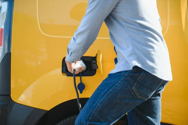 Man charges an electric car at the charging station