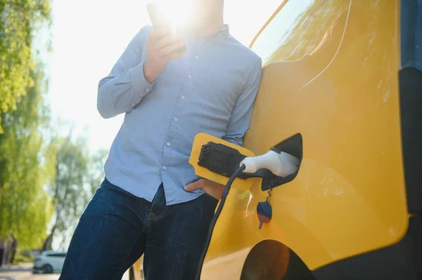 Man charges an electric car at the charging station