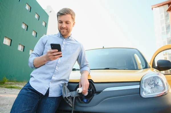 Schöner Mann Benutzt Handy Während Das Auto Geladen Wird — Stockfoto