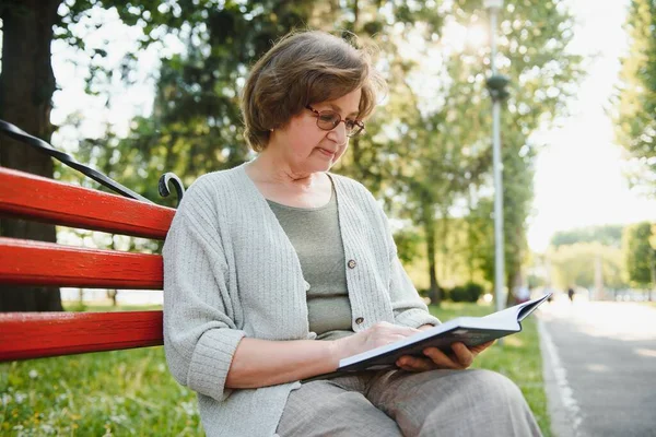 Pensionerad Kvinna Läser Bok Bänken — Stockfoto