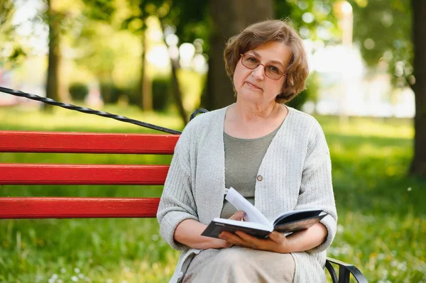 Pensionerad Kvinna Läser Bok Bänken — Stockfoto