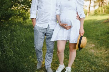 Mutlu ve genç hamile çift doğada sarılıyorlar..