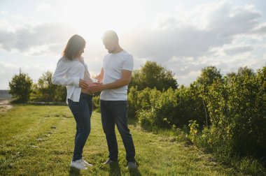 Mutlu ve genç hamile çift doğada sarılıyorlar..