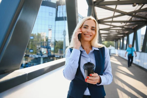 Beautiful Woman Going To Work With Coffee Walking Near Office Building. Portrait Of Successful Business Woman Holding Cup Of Hot Drink