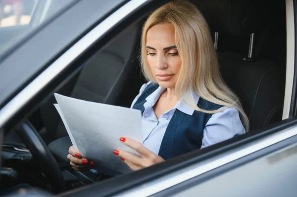 Fashion business woman with financial papers by her car.