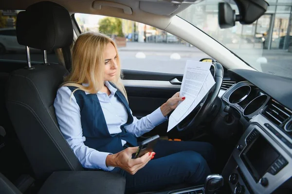 Fashion business woman with financial papers by her car.