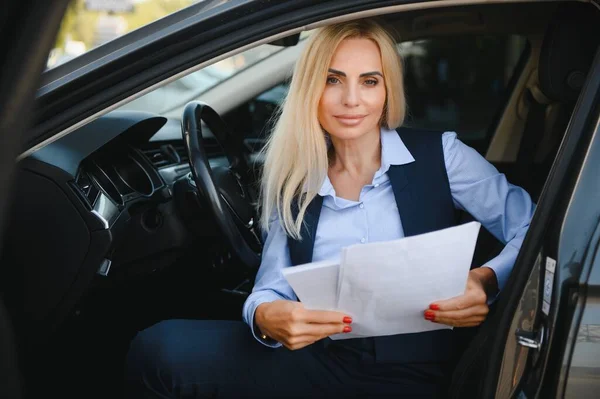 Fashion business woman with financial papers by her car.