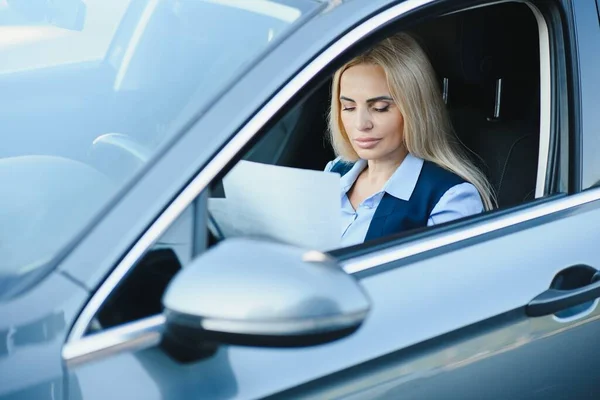 Fashion business woman with financial papers by her car.