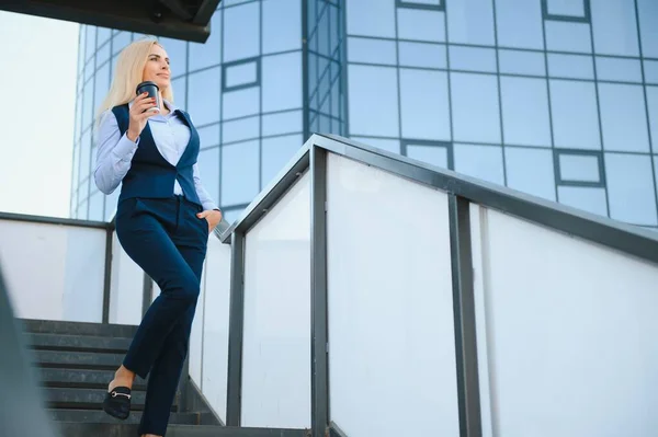 Close up portrait of a serious business woman in blue suit standing in the city.