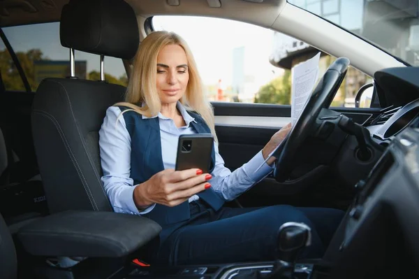 Fashion business woman with financial papers by her car.