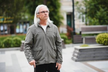 Park yerinde dinlenirken elinde baston tutan yaşlı adamın portresi.