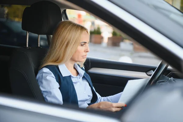 Fashion business woman with financial papers by her car.