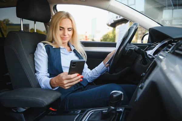 Serious business woman in the car examines important documents