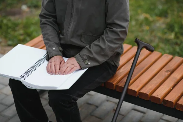 Blinded man reading by touching braille book.
