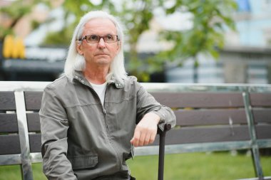 Yaşlı bir adam bir bahar parkında bastonla yürüyor.