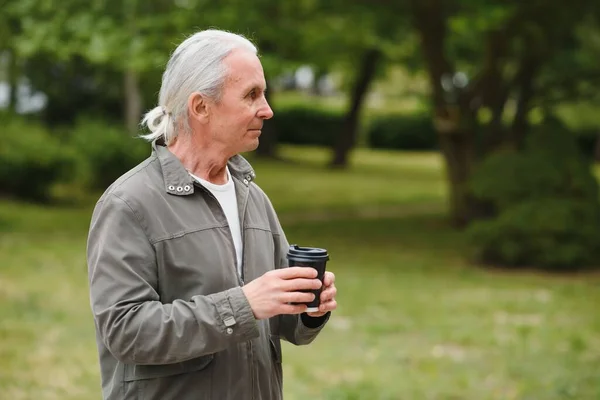 Senior man in stylish outfit holding cup of coffee