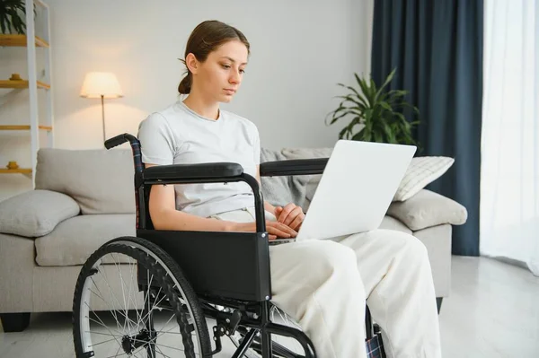 女性自由职业程序员坐在轮椅上 在家里用计算机编写网络游戏 — 图库照片