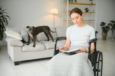 Oturma odasında tekerlekli sandalyedeki genç kadın.