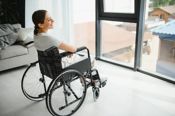 Mulher Olhando Para Longe Enquanto Sentada Cadeira Rodas Casa — Fotografia de Stock