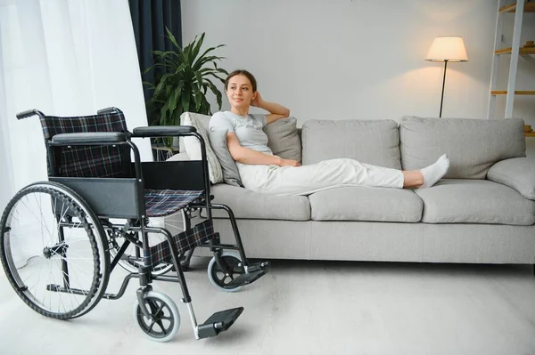 Nainen Yrittää Istua Pyörätuolissa Sohvalta — kuvapankkivalokuva