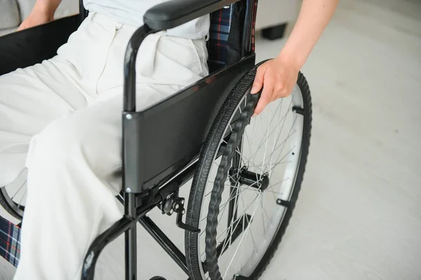Woman in wheelchair\'s hand on wheel close up.