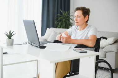 Dizüstü bilgisayar, çalışma tekerlekli sandalyede olumlu yaşlı kadın bu serbest meslek sahibi, online.