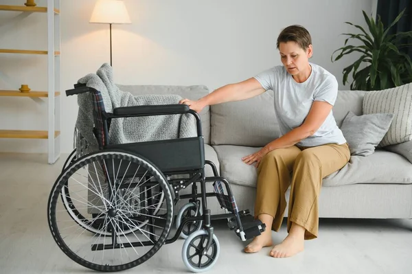 老妇人想从沙发上坐上轮椅 — 图库照片
