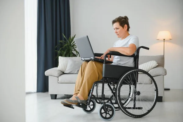 Mulher Meia Idade Usando Laptop Sentado Cadeira Rodas Casa — Fotografia de Stock