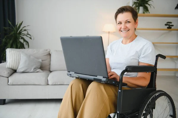 积极的老年妇女在轮椅上工作的笔记本电脑 它的自由职业者 — 图库照片