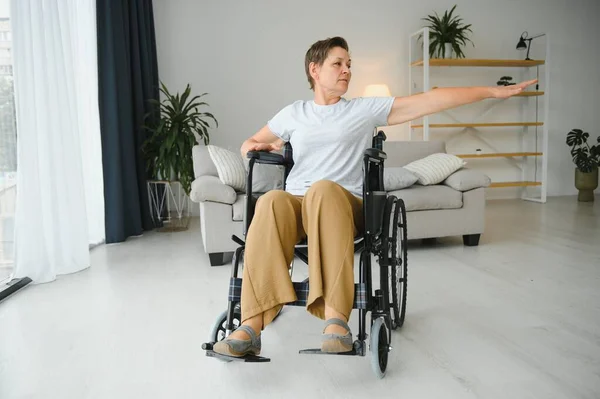 Kobieta Wózku Inwalidzkim Ćwiczy Salonie — Zdjęcie stockowe