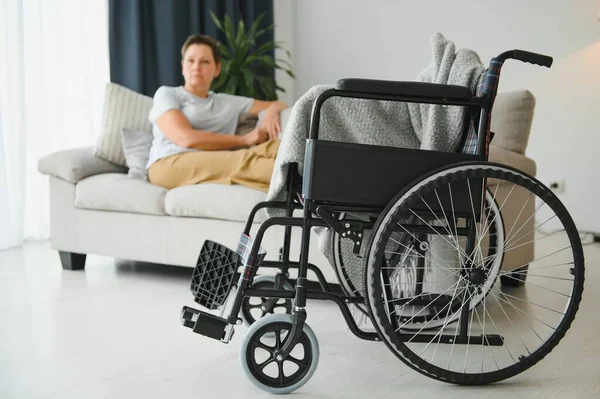 Brünette Frau Auf Couch Der Nähe Von Rollstuhl — Stockfoto