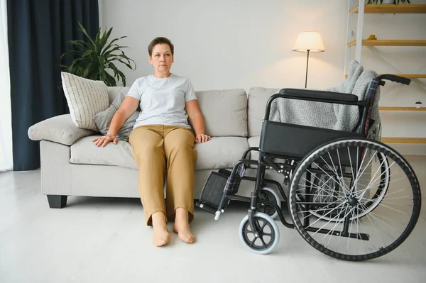 Brunette Femme Sur Canapé Près Fauteuil Roulant — Photo