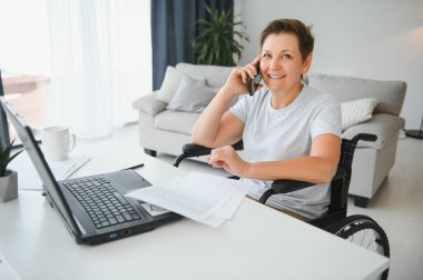 Dizüstü bilgisayar, çalışma tekerlekli sandalyede olumlu yaşlı kadın bu serbest meslek sahibi, online.