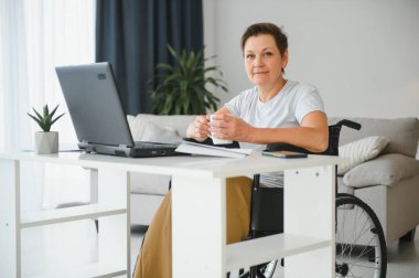 Dizüstü bilgisayar, çalışma tekerlekli sandalyede olumlu yaşlı kadın bu serbest meslek sahibi, online.