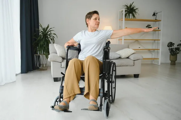 Kobieta Wózku Inwalidzkim Ćwiczy Salonie — Zdjęcie stockowe