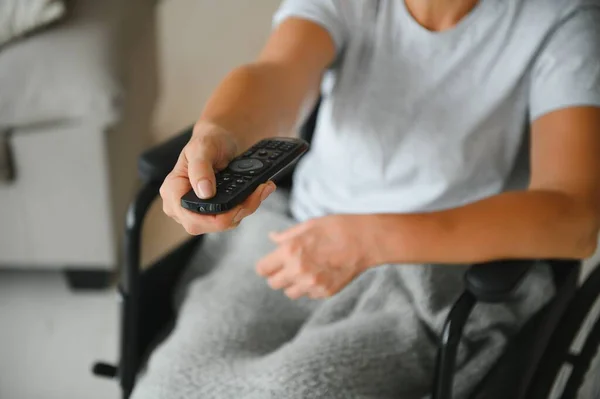 woman in wheelchair uses a tv remote control